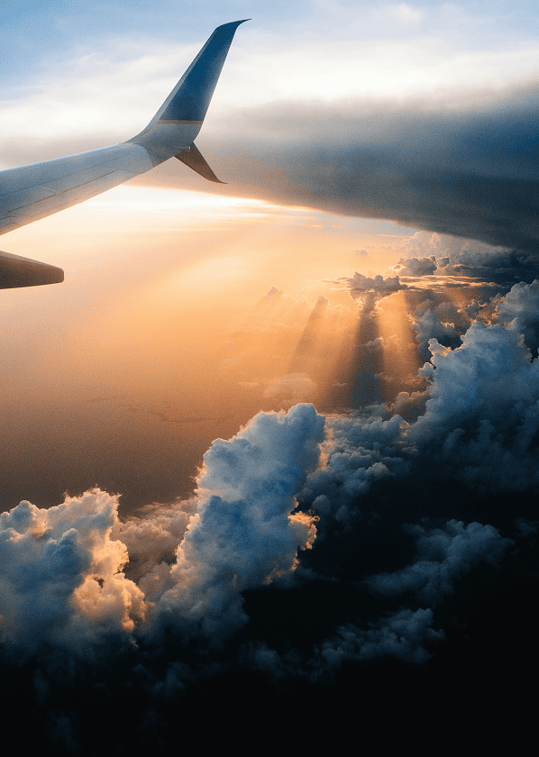 View from airplane window showing clouds and sunset sky during flight.