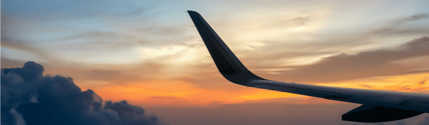 Sunset view from airplane window with wingtip during flight at dusk.