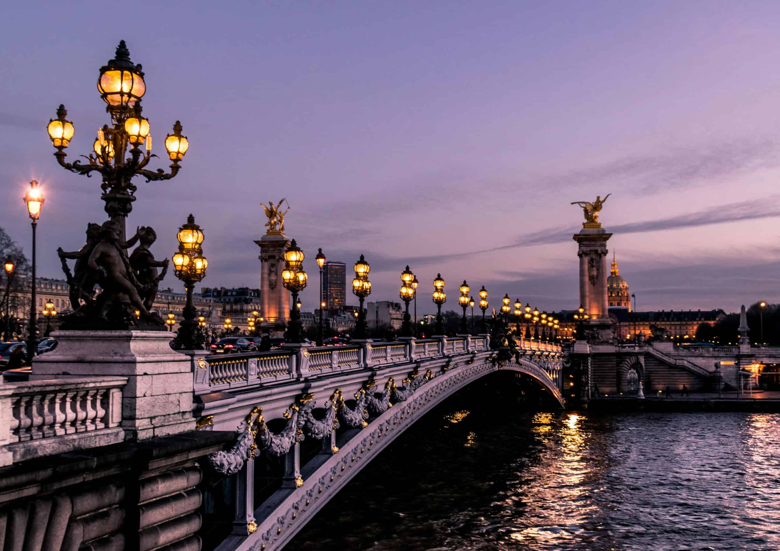 Paris Pont Alexandre III bridge with ornate lamps and sculptures at dusk.